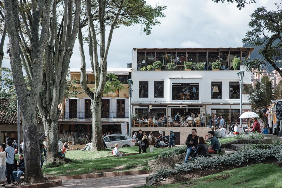 Main square in Usaquén, Bogotá with white colonial buildings housing restaurants and outdoor dining areas.