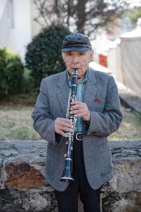 Elderly man playing clarinet on a street in Usaquén neighborhood.