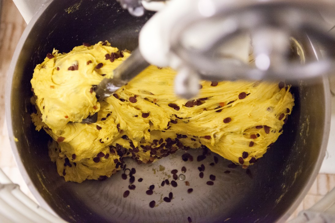 Yellow panettone dough with dried fruit in a metal mixing bowl during preparation.