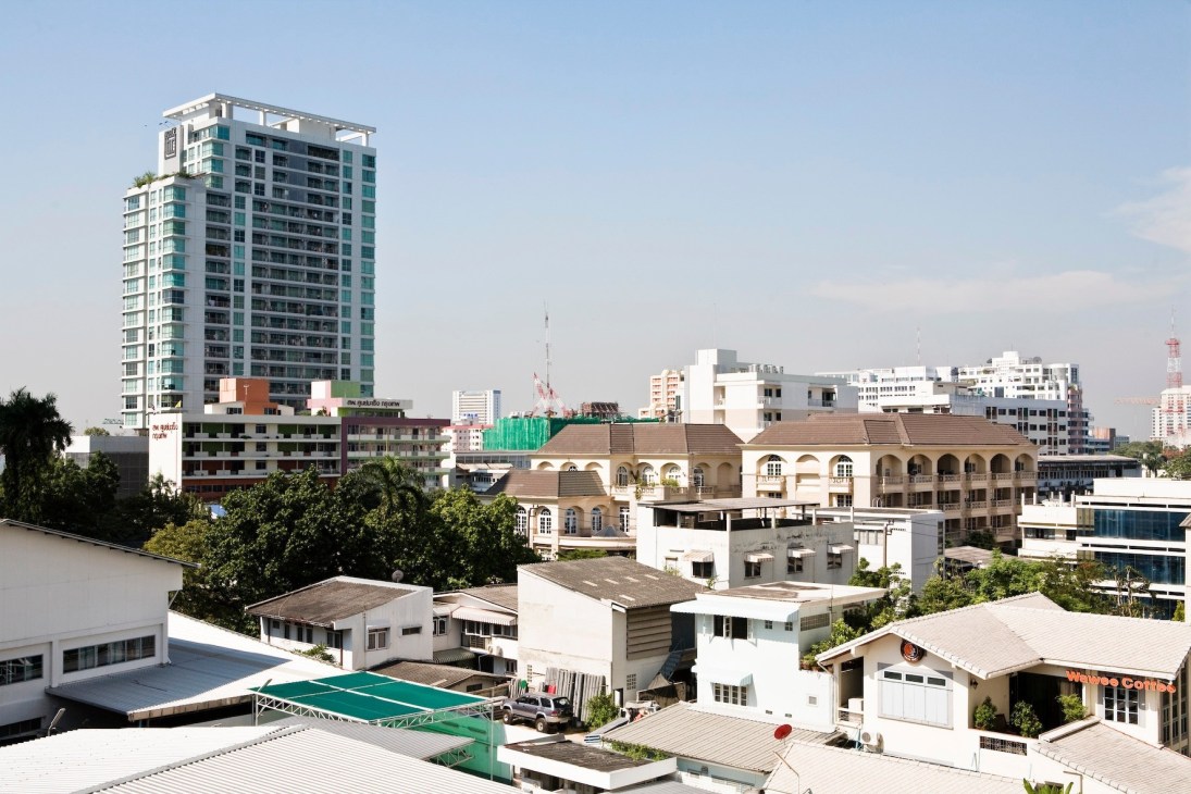 Bangkok's Ari neighbourhood skyline showing modern high-rise apartment buildings mixed with traditional lower-rise architecture and green vegetation.