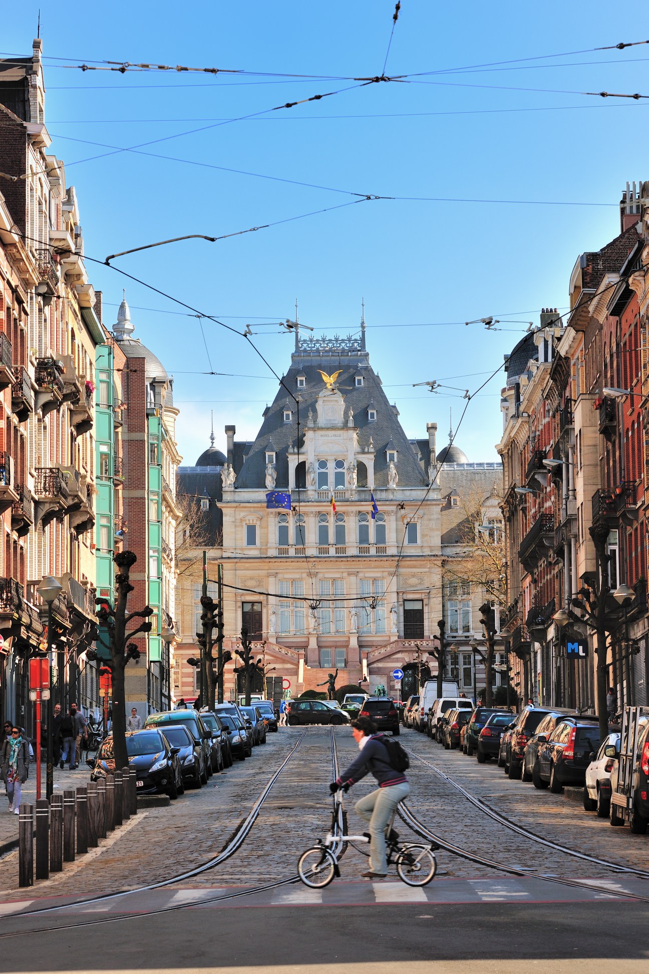 Street view of Saint-Gilles with the imposing city hall building in the background and tram tracks in foreground.