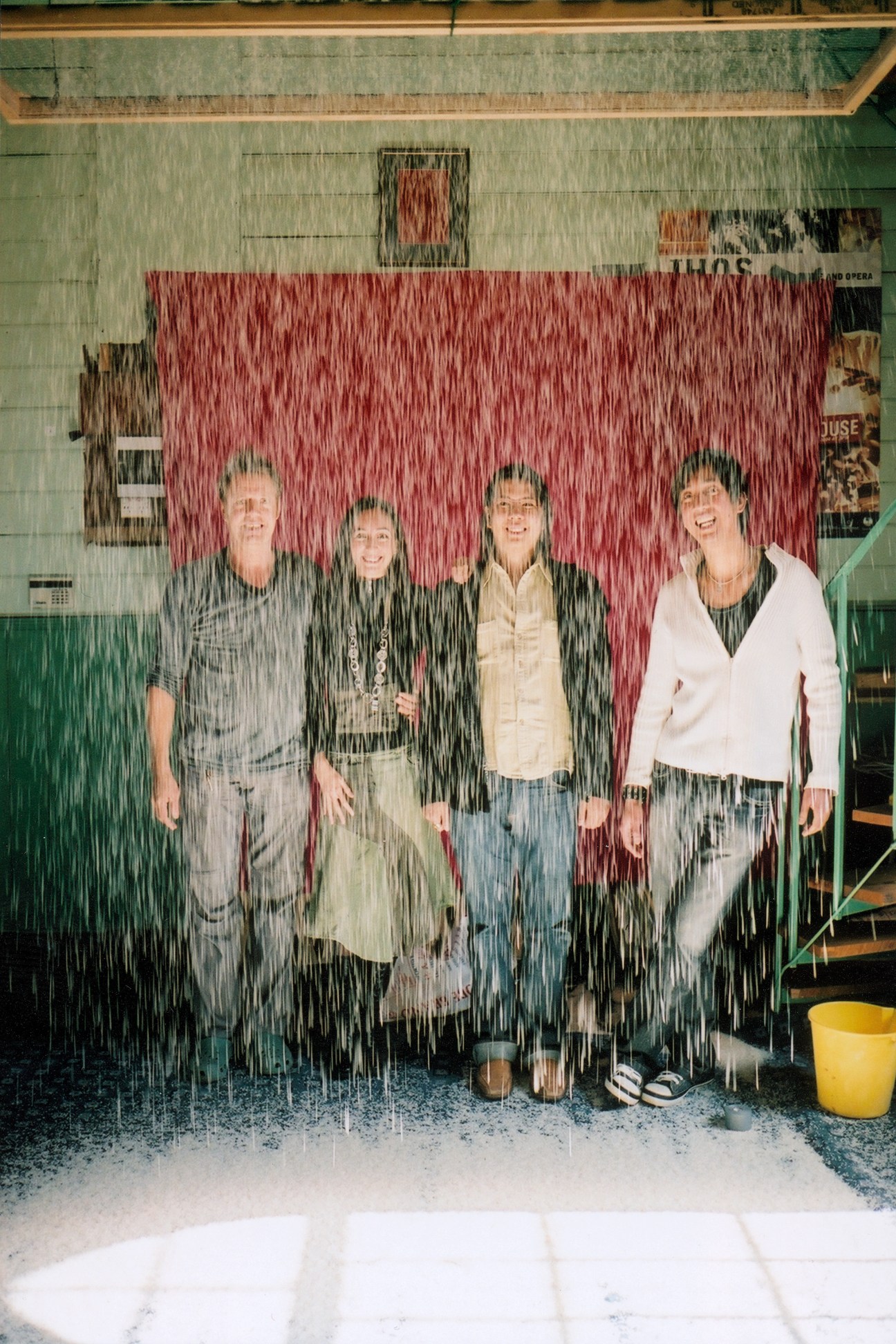 Four people standing in front of a red wall during IHOS Music Theatre & Opera rehearsal, with composer Thanapoom Sirichang on the right.