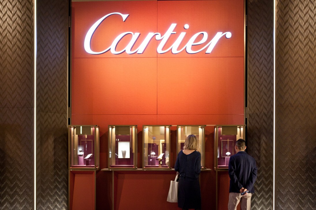 Cartier illuminated storefront display with two visitors viewing watches at SIHH