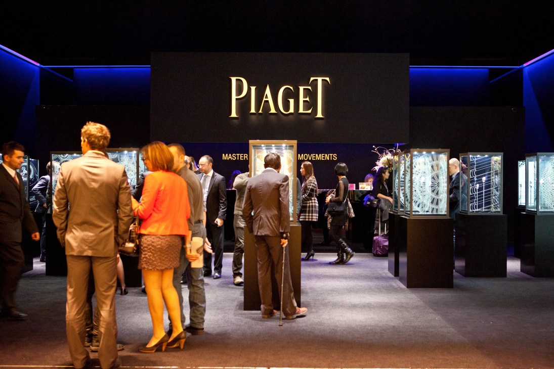 Visitors browse the Piaget stand at SIHH with illuminated display cases and Master Movements signage.
