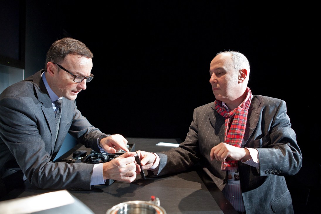 Two men in business suits examining and trying on watches at the IWC stand at SIHH.