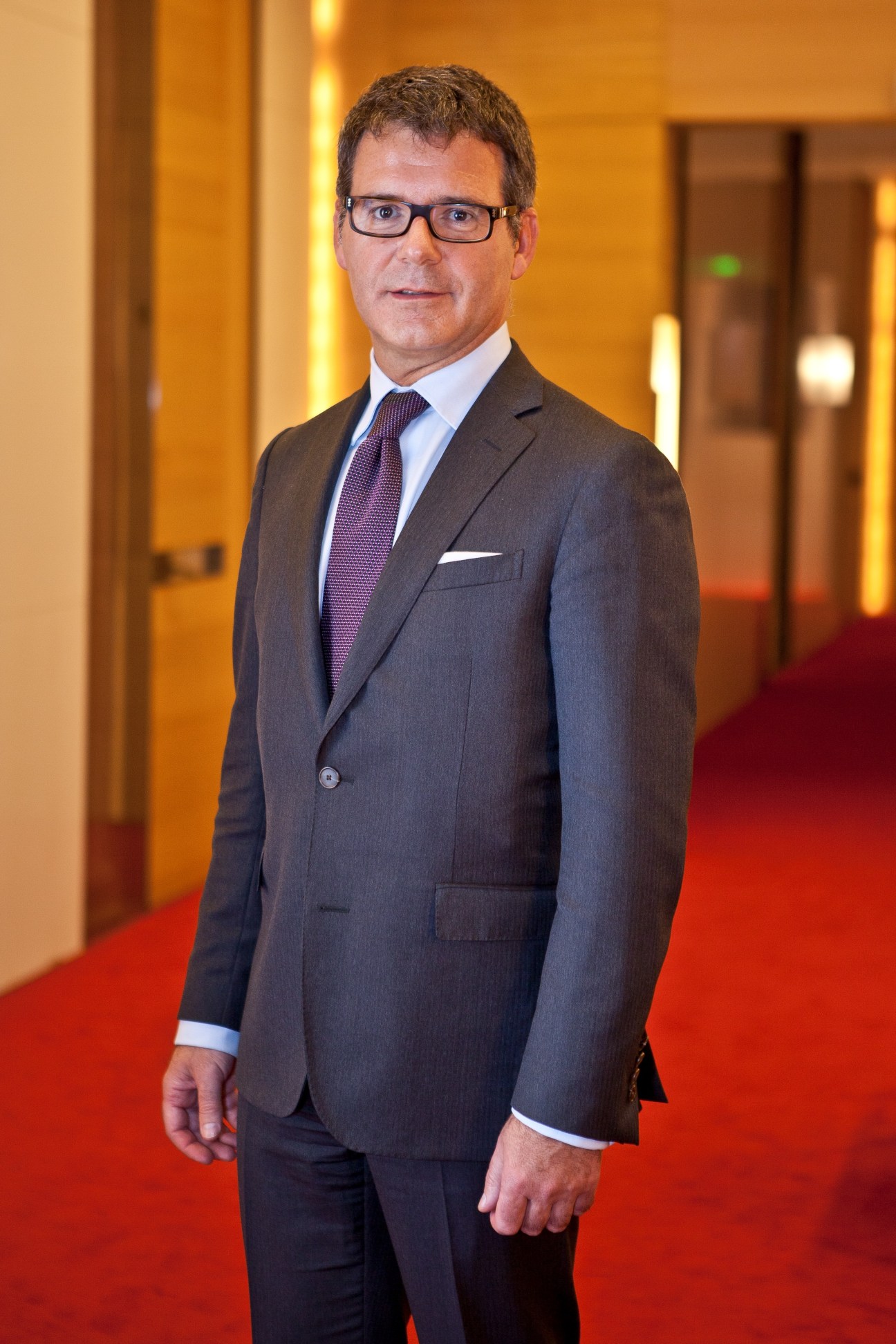Pierre Rainero, Cartier's image, style and heritage director, standing in a formal grey suit and purple tie.