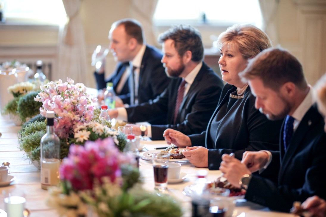 Norwegian prime minister Erna Solberg dining with officials at a formal table set with Figgjo plates and floral centerpieces.