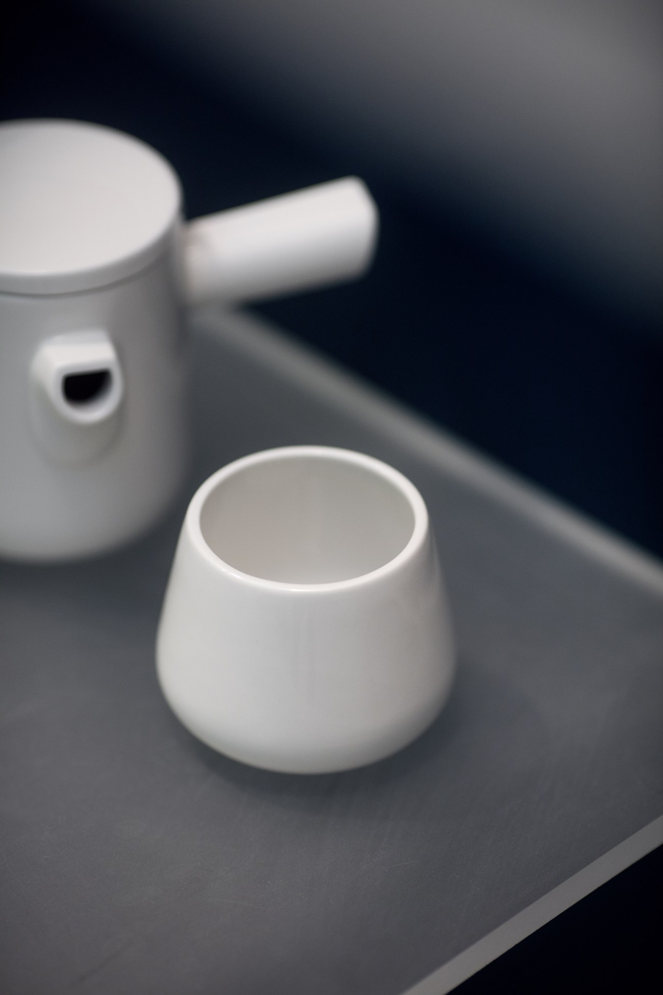 White porcelain cups and tableware displayed on a dark surface in Figgjo showroom.
