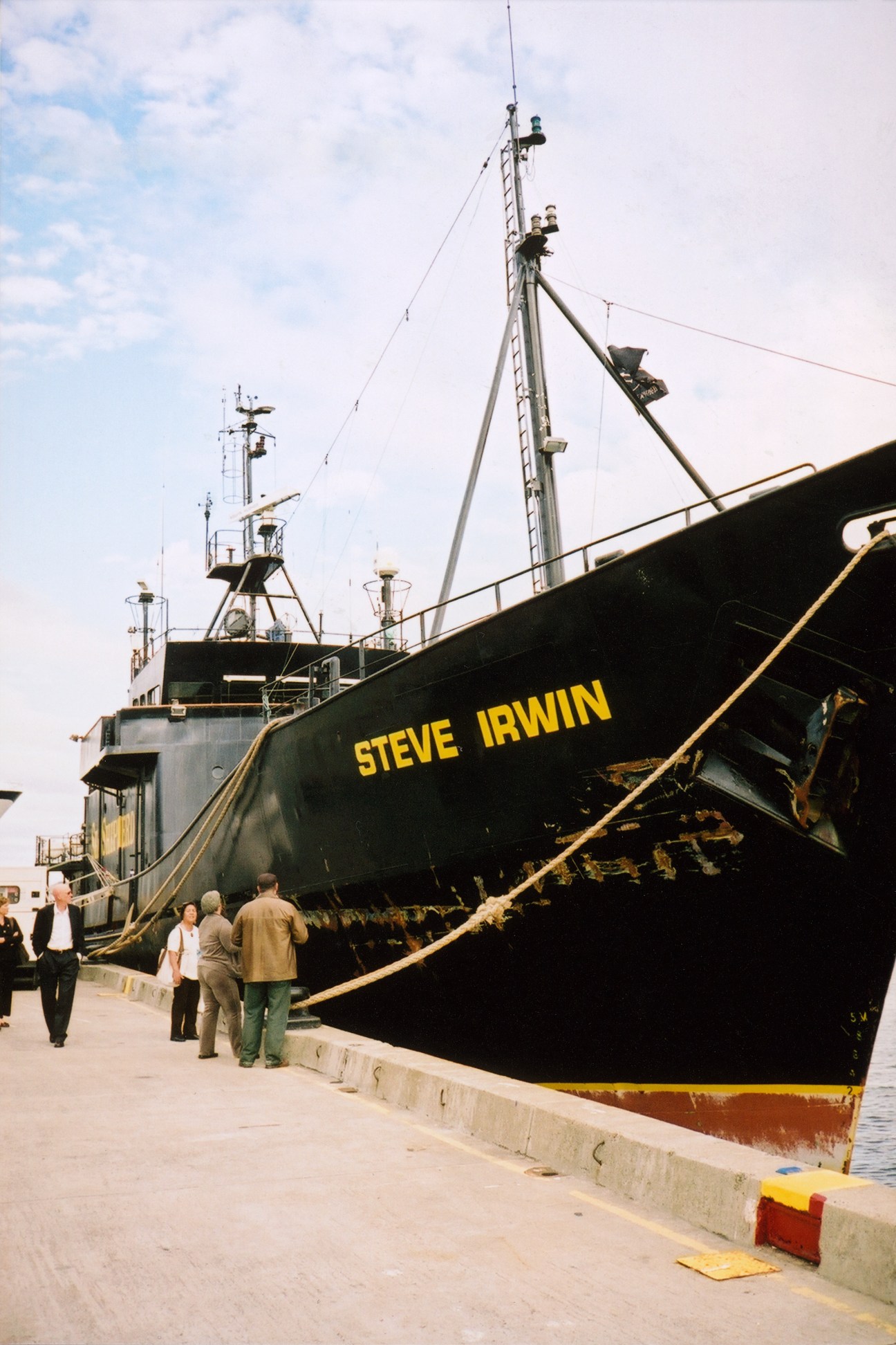 The Steve Irwin Sea Shepherd vessel docked at port with people standing nearby on the quay.