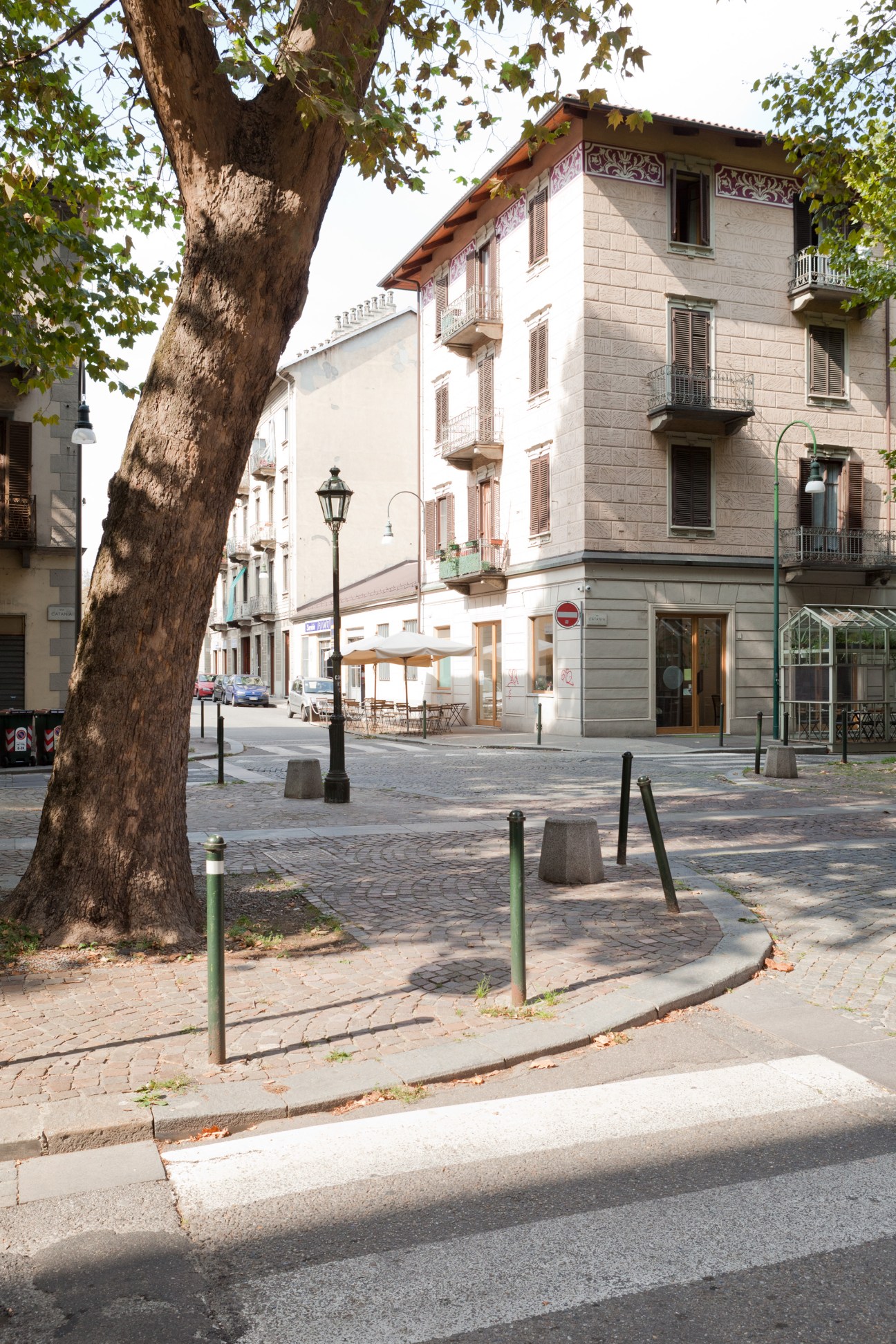 Tree-lined street in Turin's Borgo Rossini district with historic buildings and outdoor café seating.