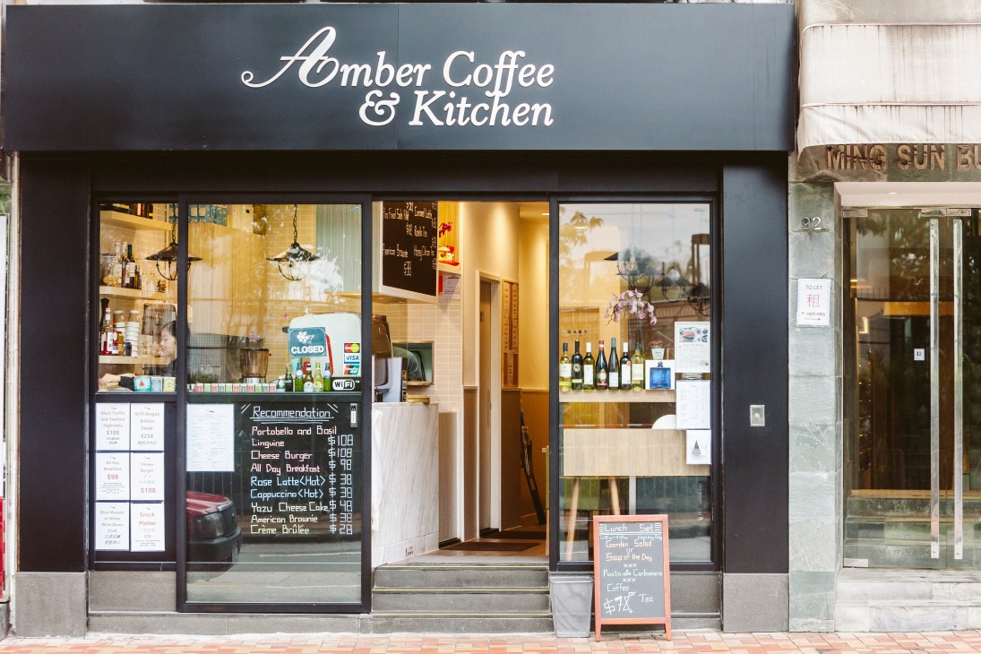 Amber Coffee & Kitchen storefront with dark exterior, large windows displaying menu boards and wine bottles on Tung Lo Wan Road in Hong Kong's Tai Hang neighbourhood.