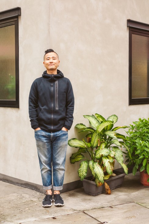 Dick Fai, founder of Seesaw Post Production, standing against a cream-colored wall in Hong Kong's Tai Hang neighbourhood.