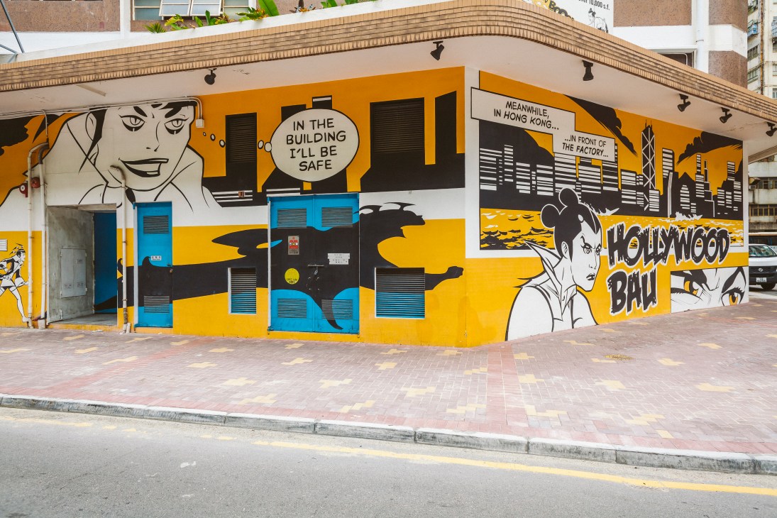 Colorful mural by comic artist Mauro Marchesi featuring yellow and black geometric shapes with stylized faces and text.