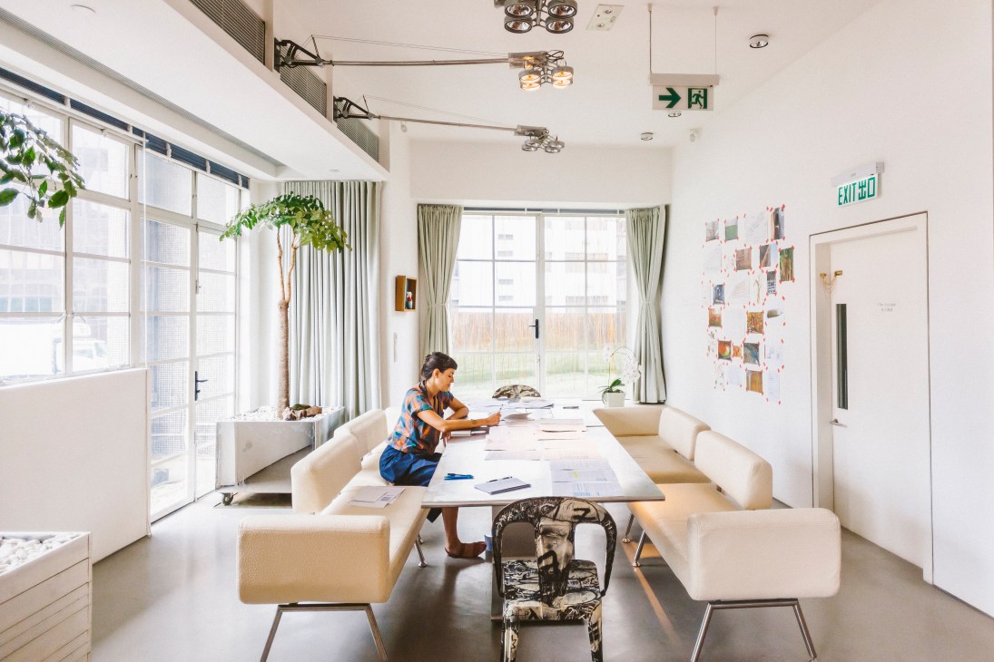 Artist and writer Malak Helmy works at a desk in a bright studio space at Spring Workshop in Hong Kong.