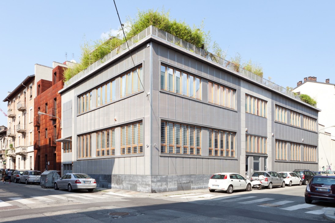 Modern loft conversion in Borgo Rossini with green rooftop, metal and glass facade, parked cars in front.