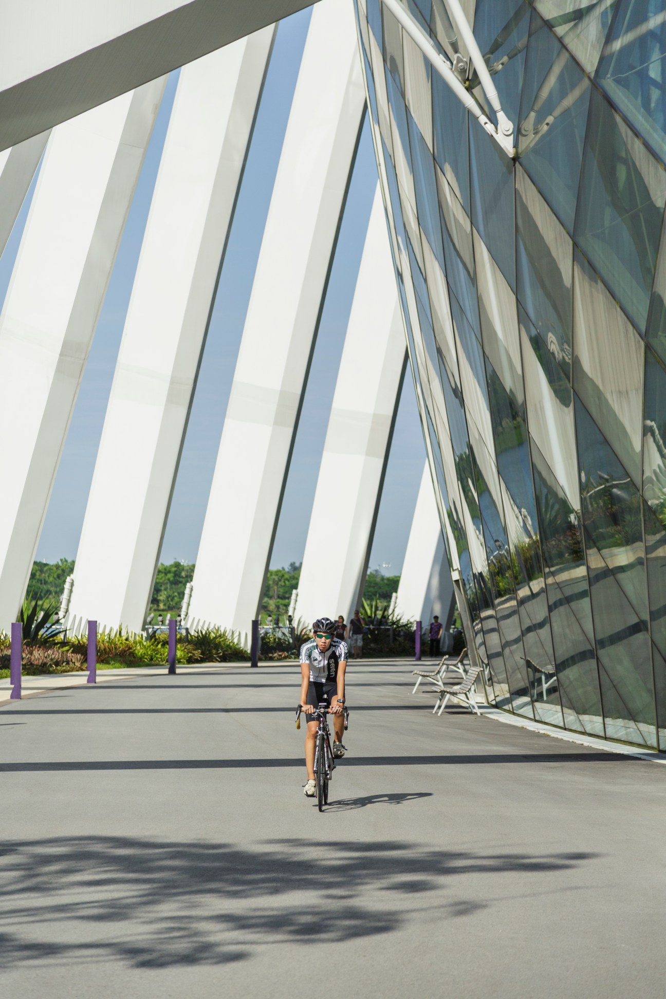 Cyclist riding past the curved white exterior of Gardens by the Bay's Flower Dome in Singapore.