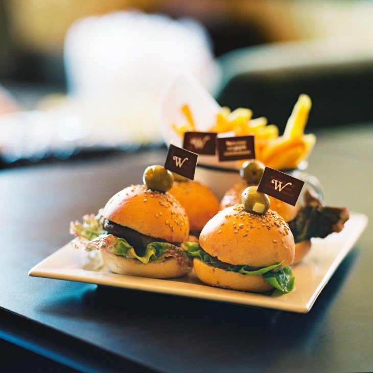 Two gourmet slider burgers with W flags on a plate with fries at El Walterio.