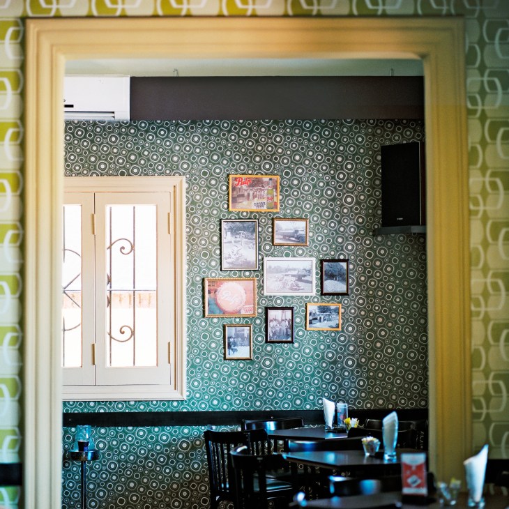 Interior of El Walterio restaurant showing retro wallpaper with geometric patterns and vintage photographs on the wall.
