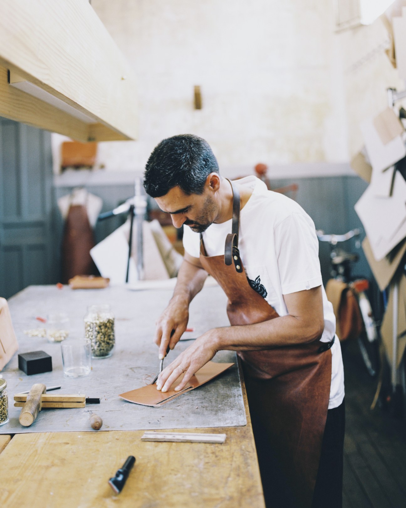 David Iglesias Resina cuts leather at his workbench in the Oficio Studio workshop.
