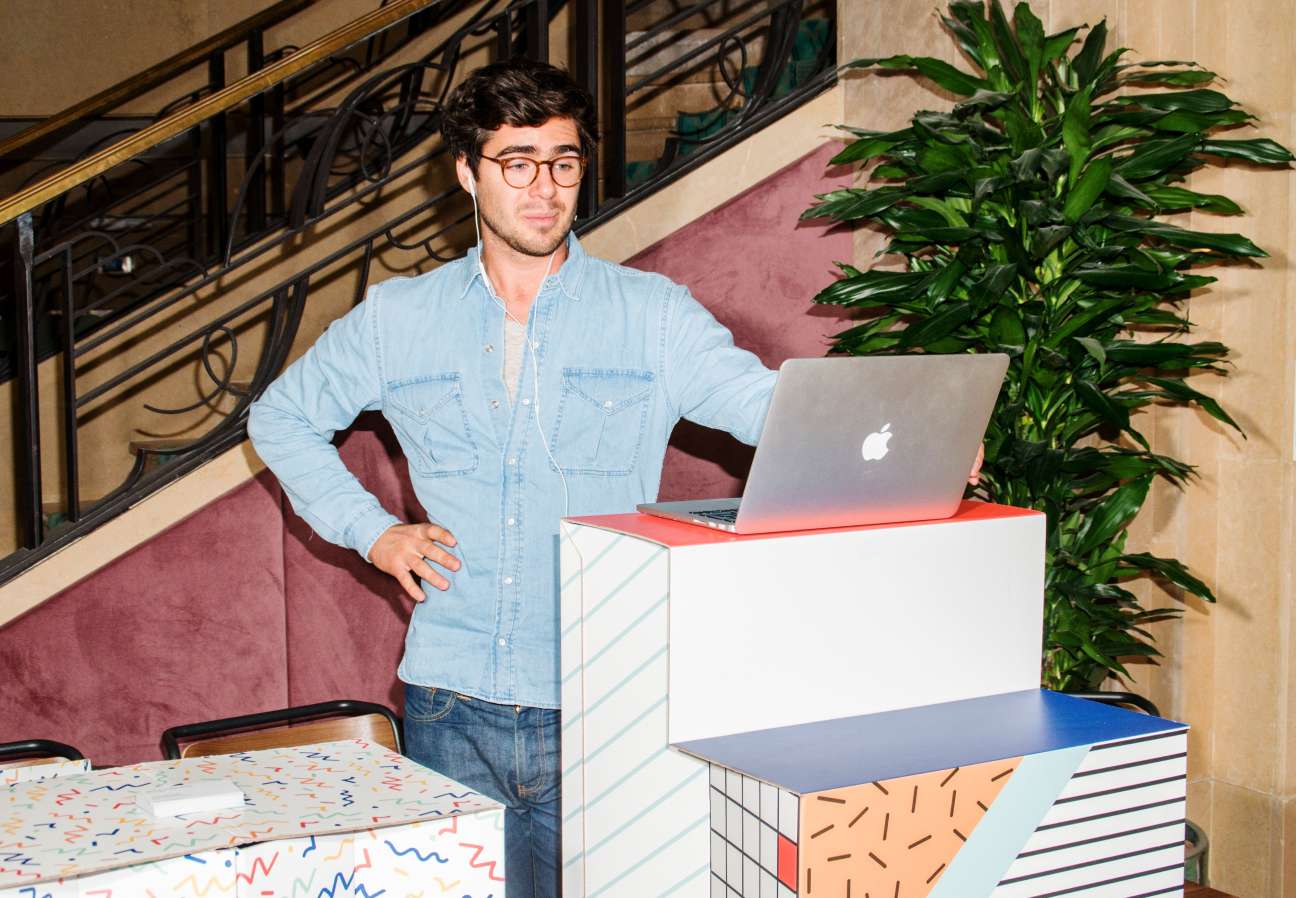 Man in light blue shirt standing at a desk with laptop in WeWork Paris office
