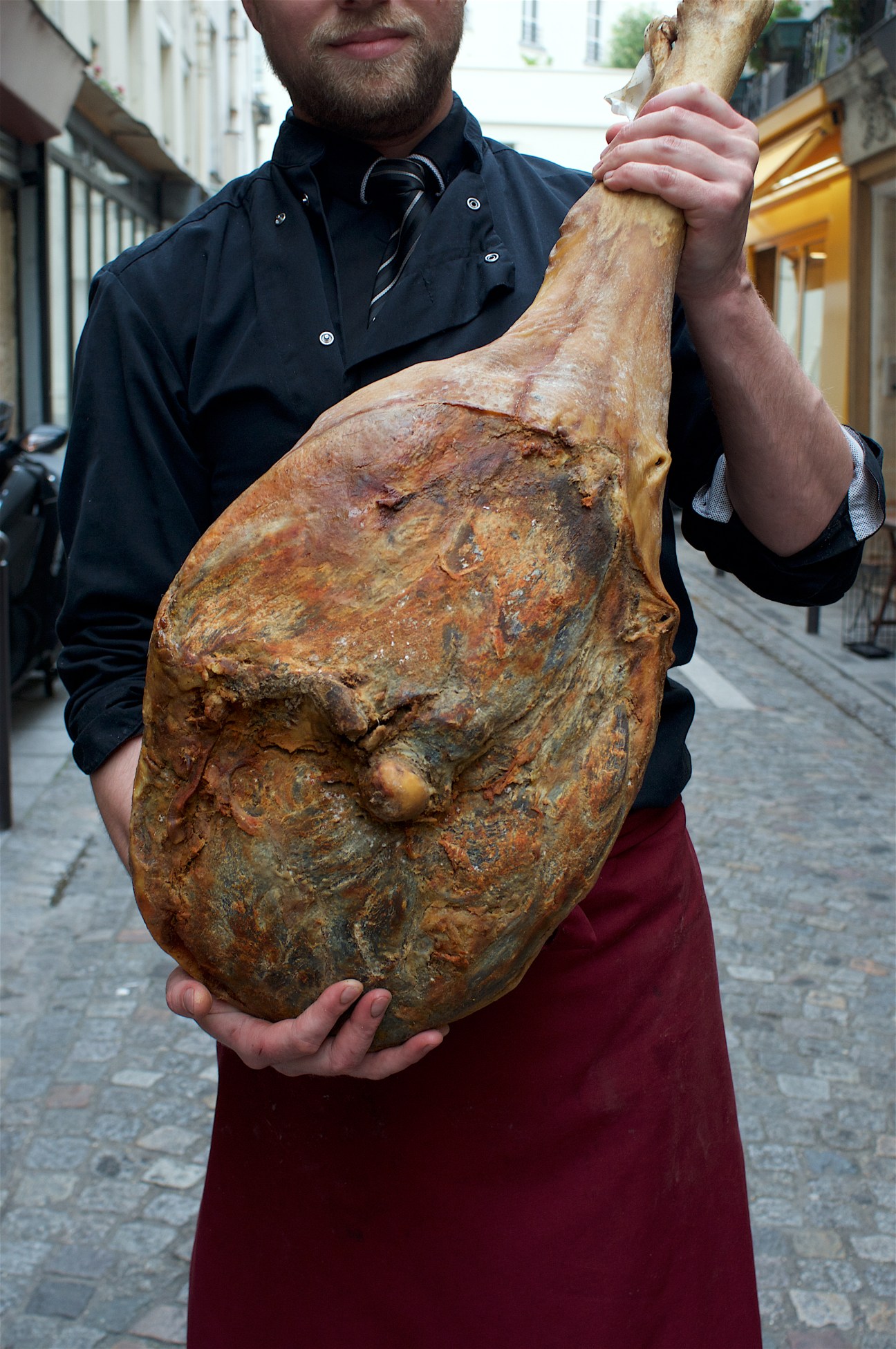 Man holding a cured ham joint on a Paris street