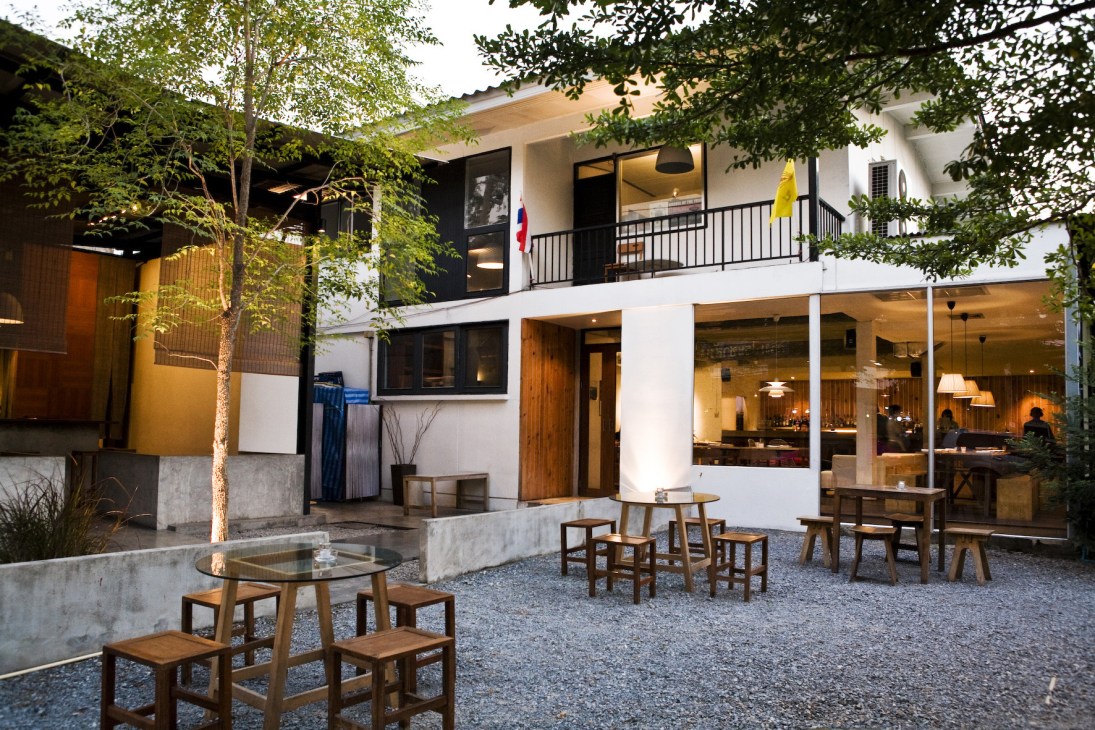 PlaDib restaurant exterior with modern white and dark facade, outdoor seating area, and surrounding greenery in Bangkok's Ari neighborhood.