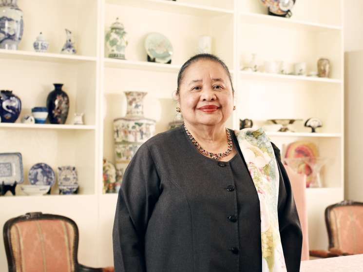 Erlinda Basilio, Philippines ambassador to China, standing in front of shelves displaying decorative porcelain vases and figurines.
