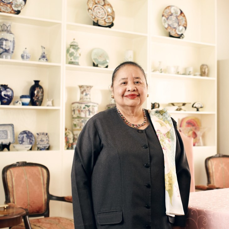Erlinda Basilio, Philippines ambassador to China, standing in front of shelves displaying decorative porcelain vases and figurines.