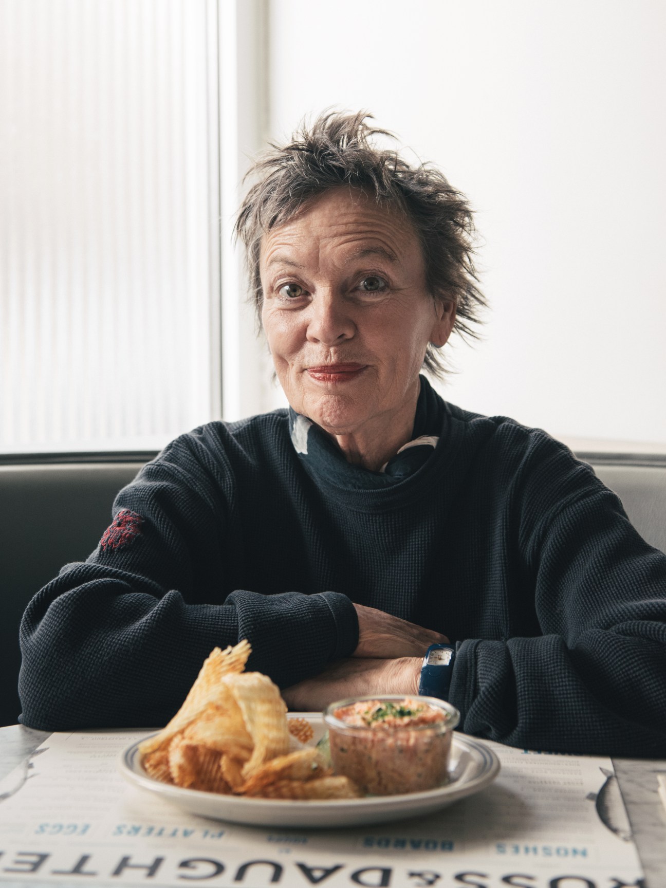 Laurie Anderson sitting at a table with a plate of food in front of her.