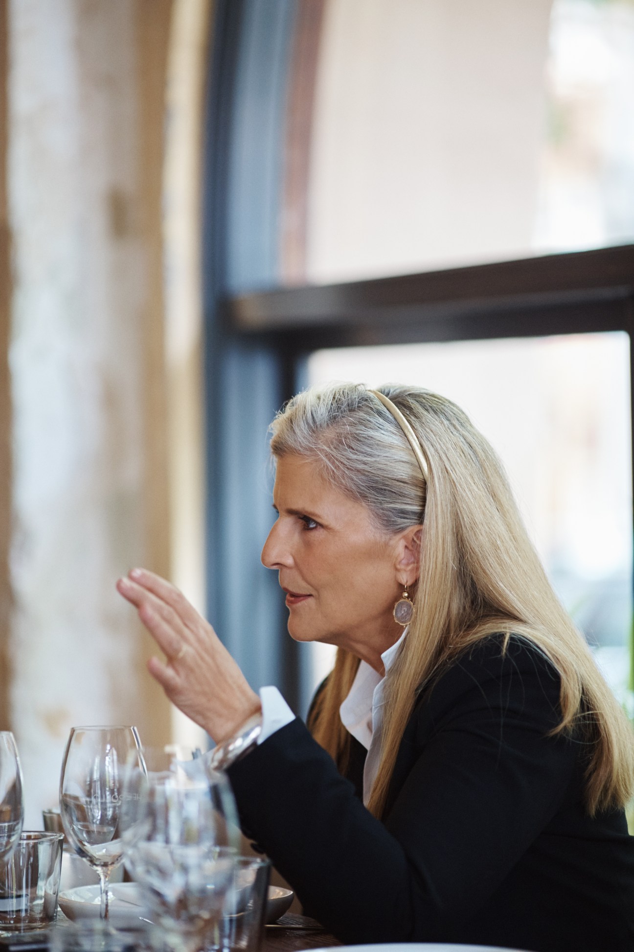 Nancy Pilcher seated at a restaurant table, gesturing while dining at The Apollo.