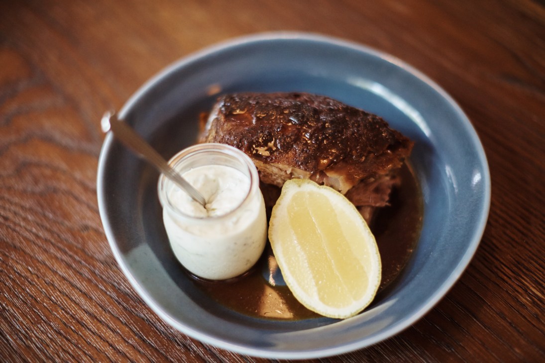 Slow-cooked lamb shoulder with yogurt and lemon served in a blue bowl on a wooden table.