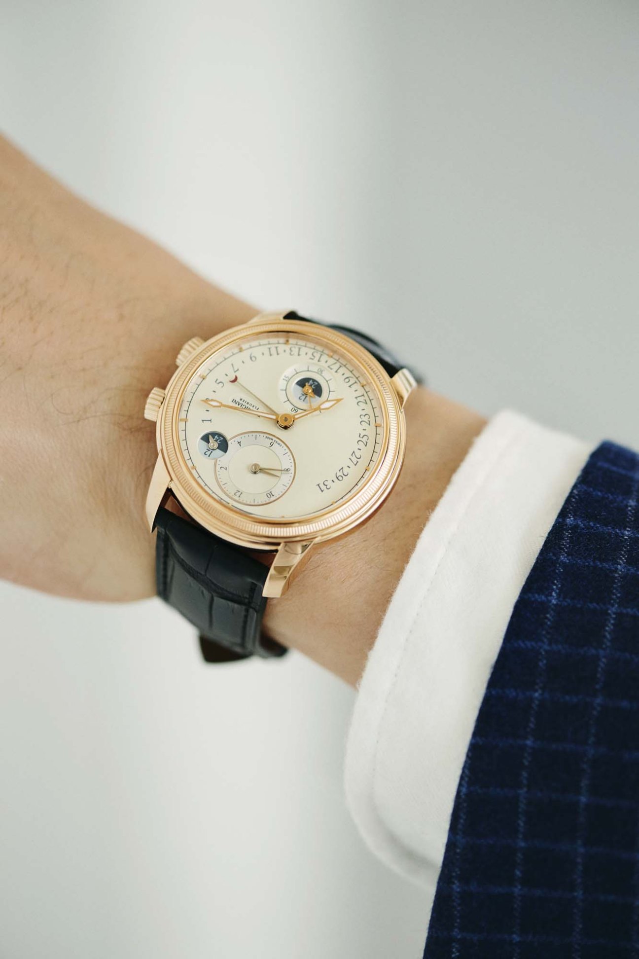 Parmigiani Fleurier luxury watch with moon phase complication on wrist with white dress shirt cuff and navy jacket