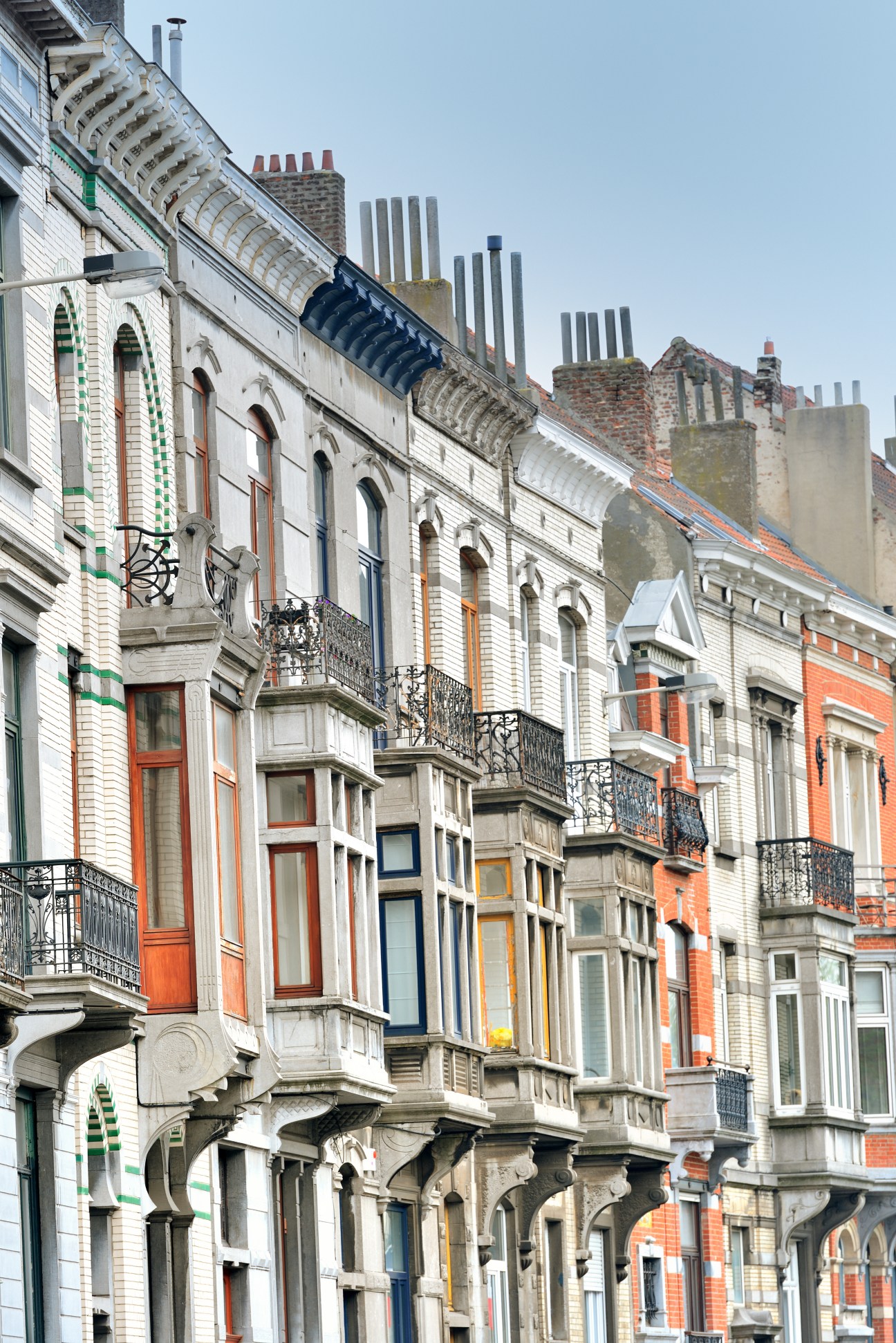 Row of colourful art nouveau townhouses with ornate facades and wrought-iron balconies in Saint-Gilles, Brussels.