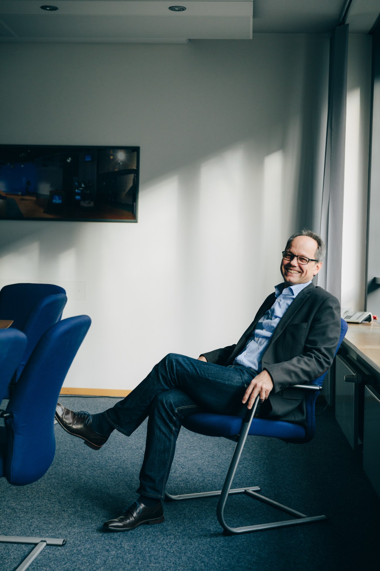 Dr Kai Gniffke, editor in chief of ARD-aktuell, sits smiling in a modern office chair.