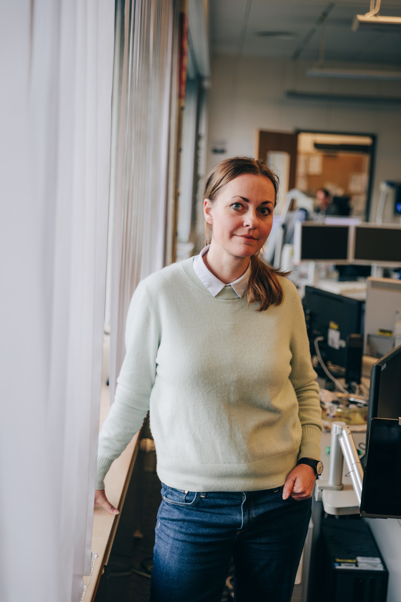 Verena Stöckigt, a woman in a cream sweater and white collared shirt, standing in the Tagesschau newsroom.