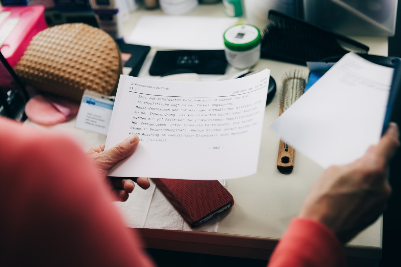 Presenter Susanne Holst holds and reads her Tagesschau news script at her desk.