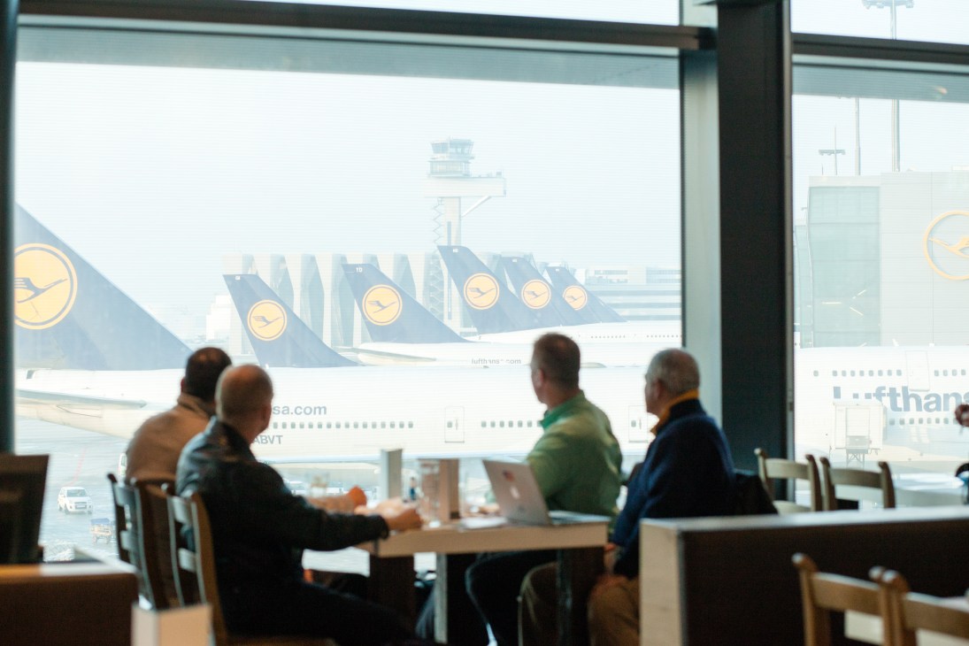 People dining at Deutsch restaurant with view of Lufthansa aircraft at Frankfurt airport.