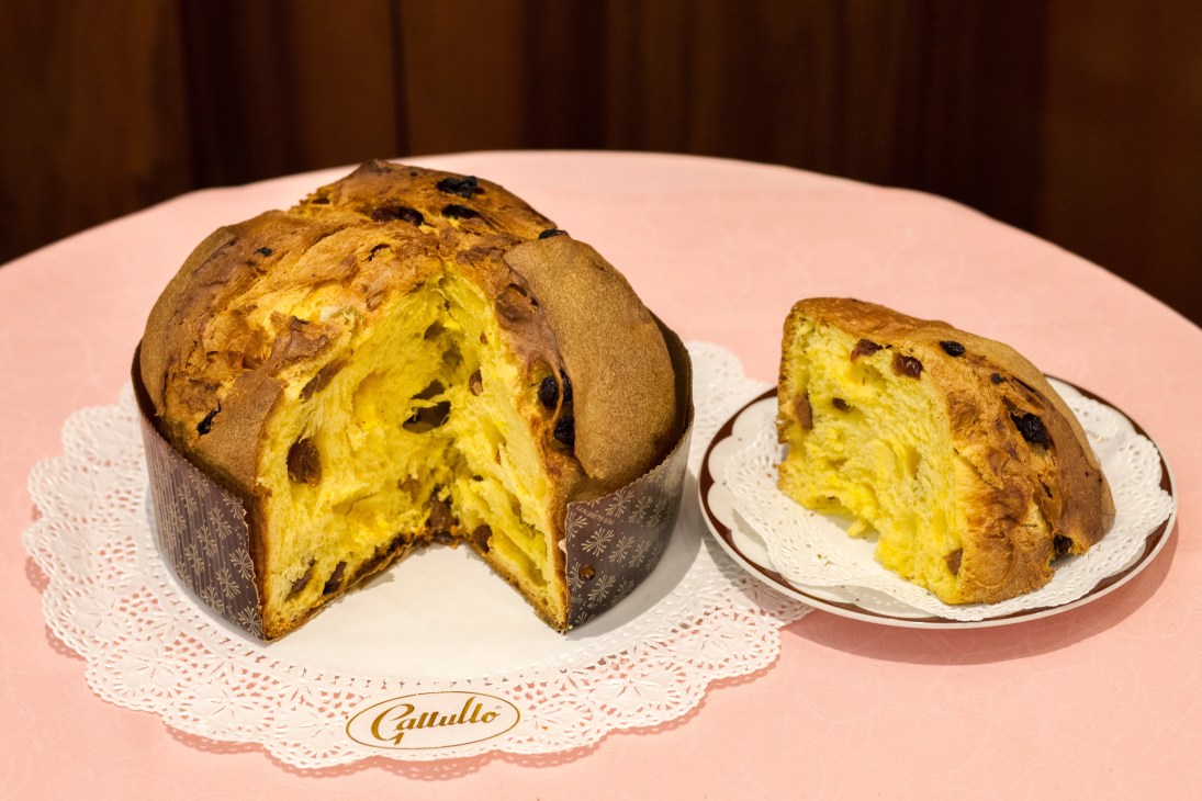 Sliced panettone from Gattullo showing candied fruit and raisins on a pink doily with the Gattullo logo.