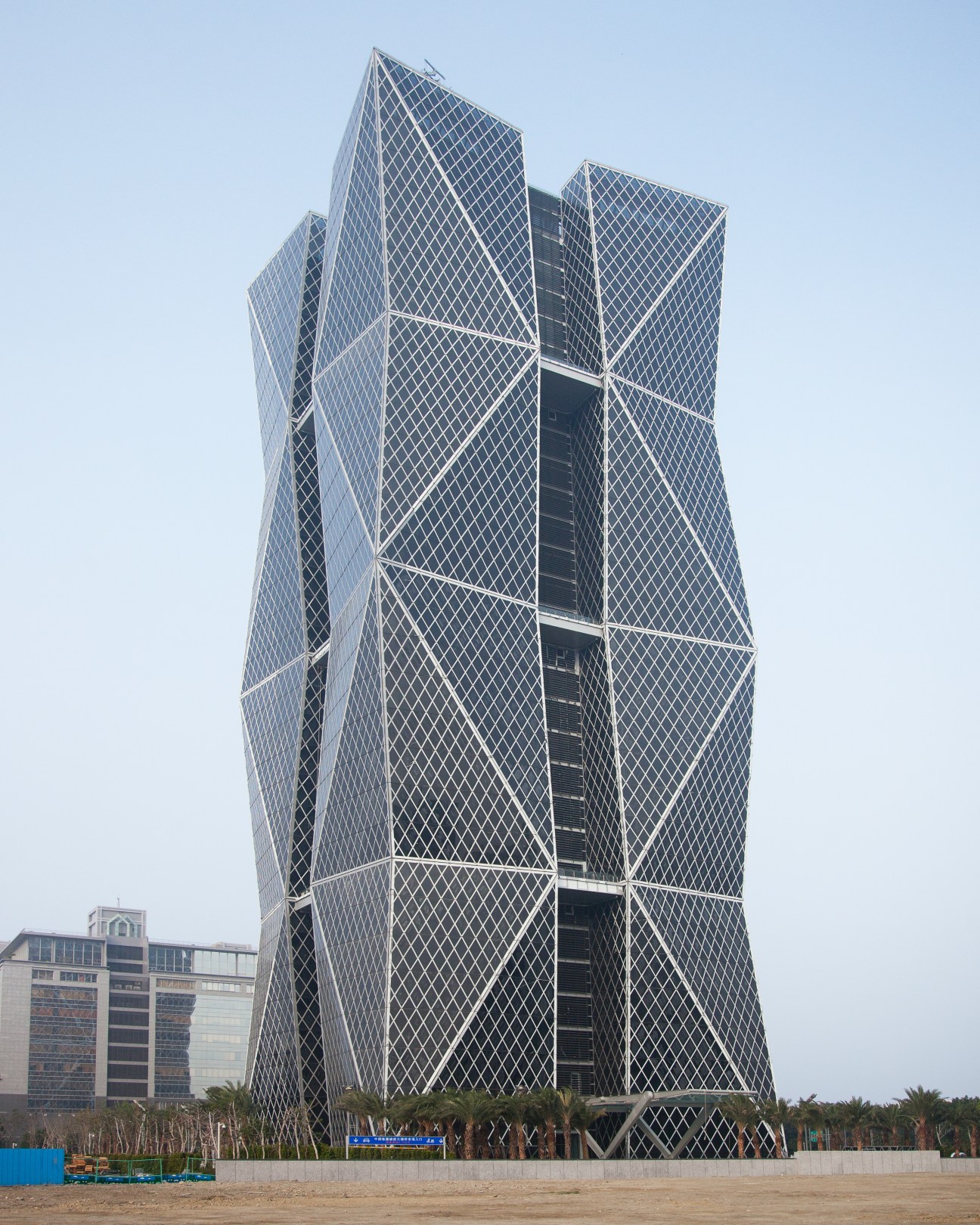 Tall modern latticed tower building with diamond-patterned facade under clear sky.