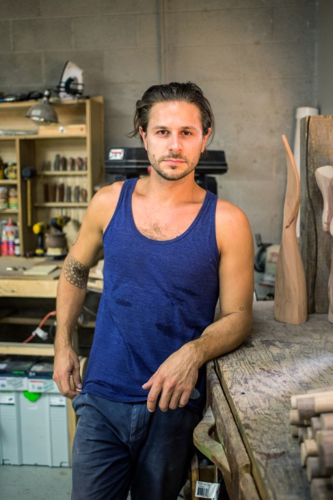 Woodworker Christian Fecht in his workshop surrounded by furniture and tools.
