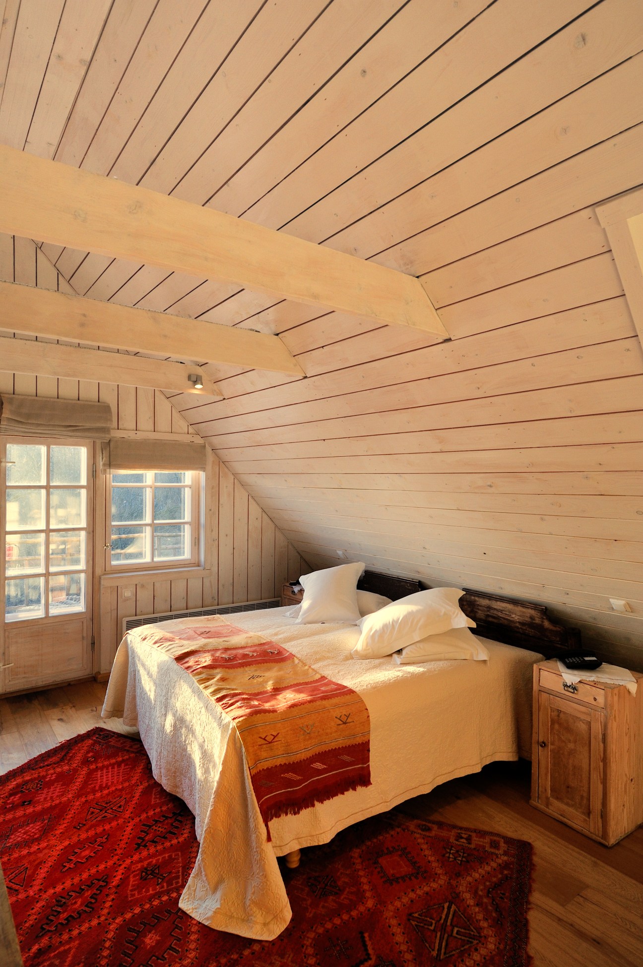 A light-filled bedroom with wooden beams and sloped ceiling at Pädaste Manor on Muhu Island, Estonia.