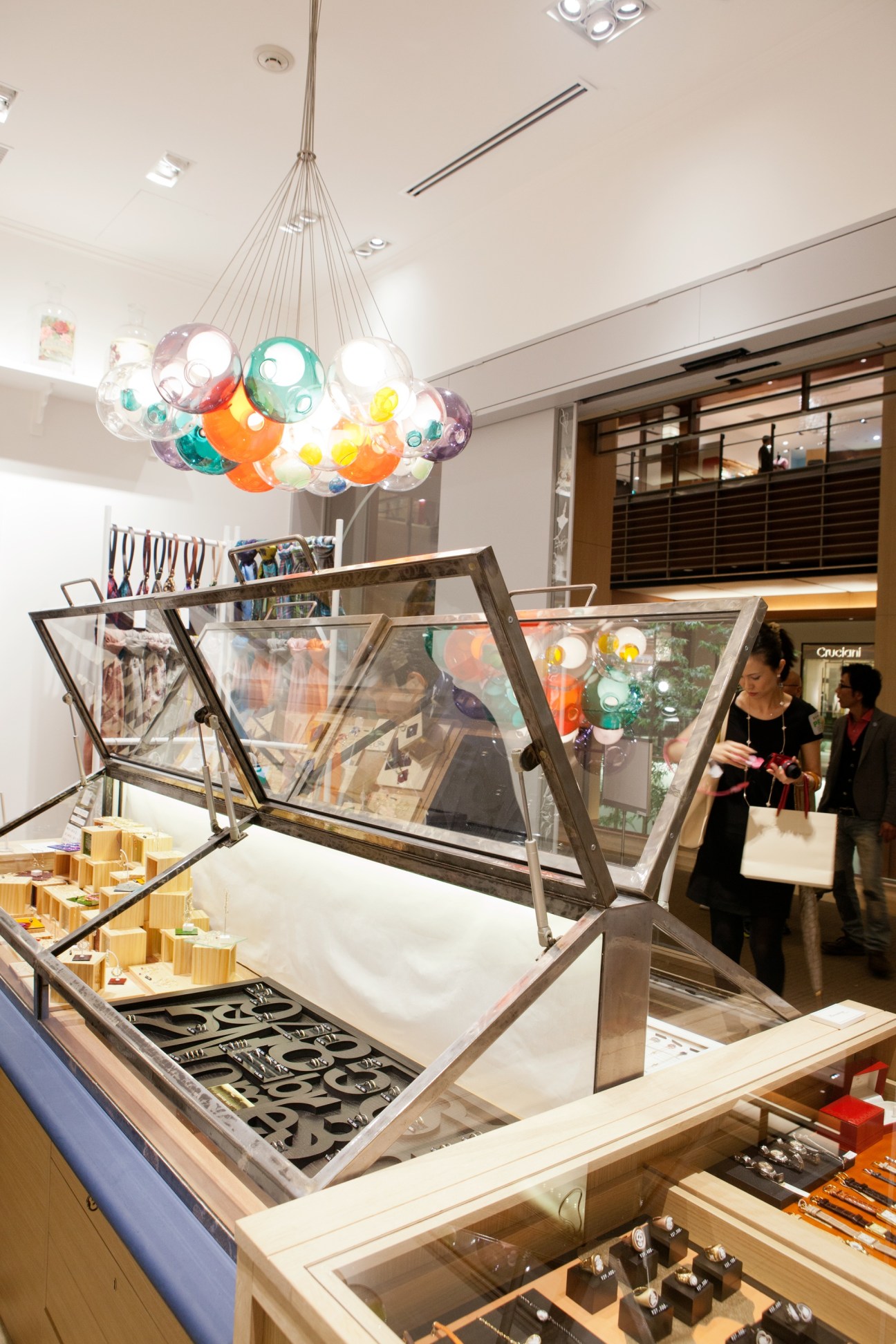 Interior of Heroomtage Deux boutique featuring a colorful Bocci chandelier and display cases with jewelry and accessories.