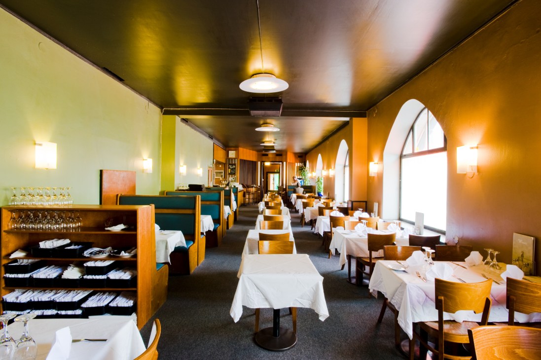 Interior of Sea Horse restaurant in Helsinki with wooden chairs, white tablecloths, and warm amber lighting.