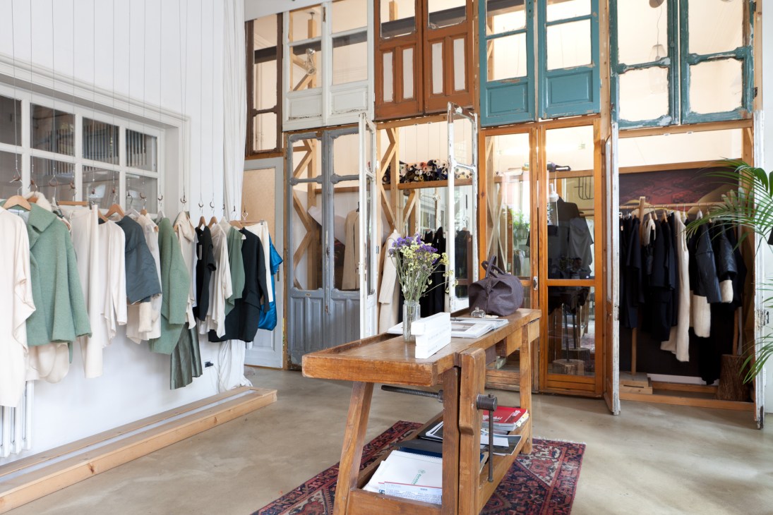 Interior of Ombradifolgia fashion boutique with clothing racks and wooden display tables in a converted industrial space.