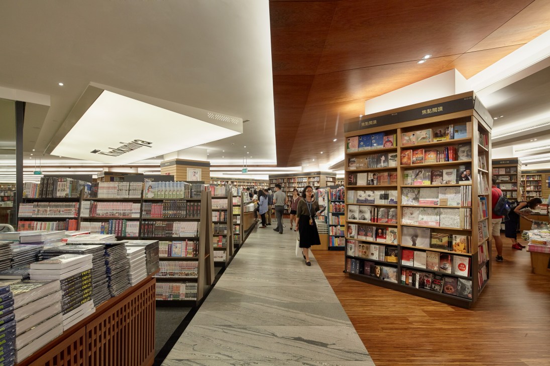 Interior of Kinokuniya bookstore showing shelving units, customers browsing, and modern lighting design.