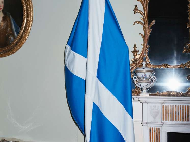 Scottish saltire flag displayed next to an ornate gilded mirror and fireplace mantel in Bute House.