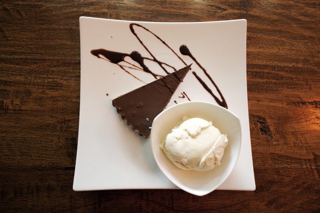 Nutella pie with vanilla ice cream served on a white plate with chocolate drizzle