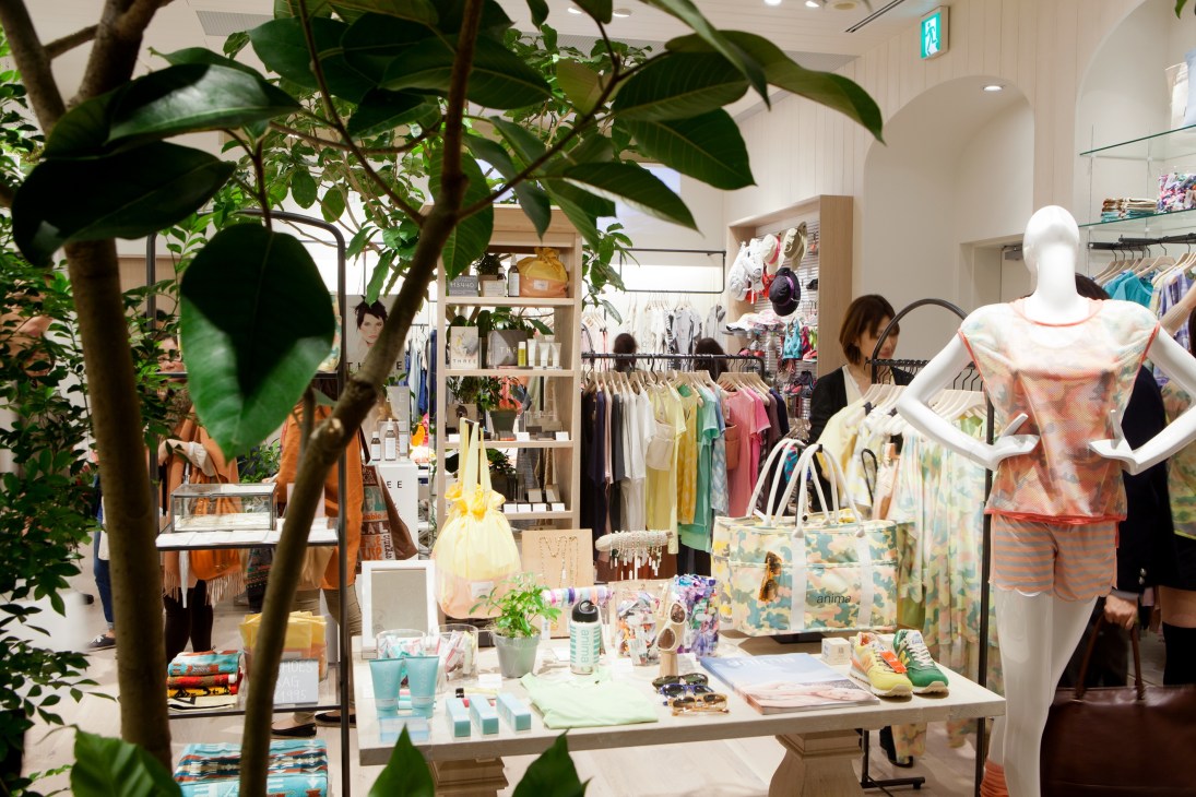 Interior of Plain People store with clothing racks, mannequins, plants, and display tables.