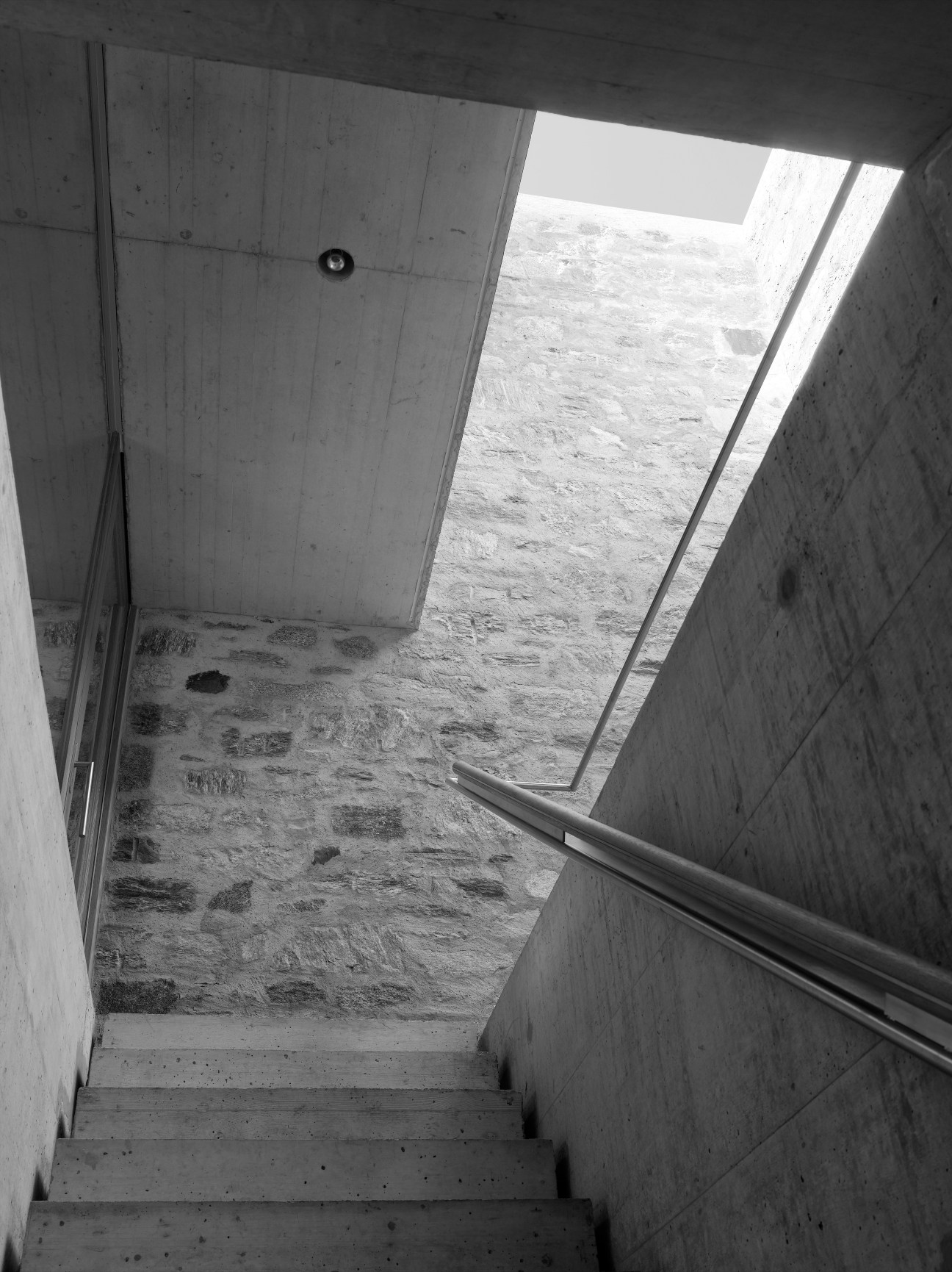 Black and white interior view of concrete staircase with skylights in Wespi de Meuron holiday retreat