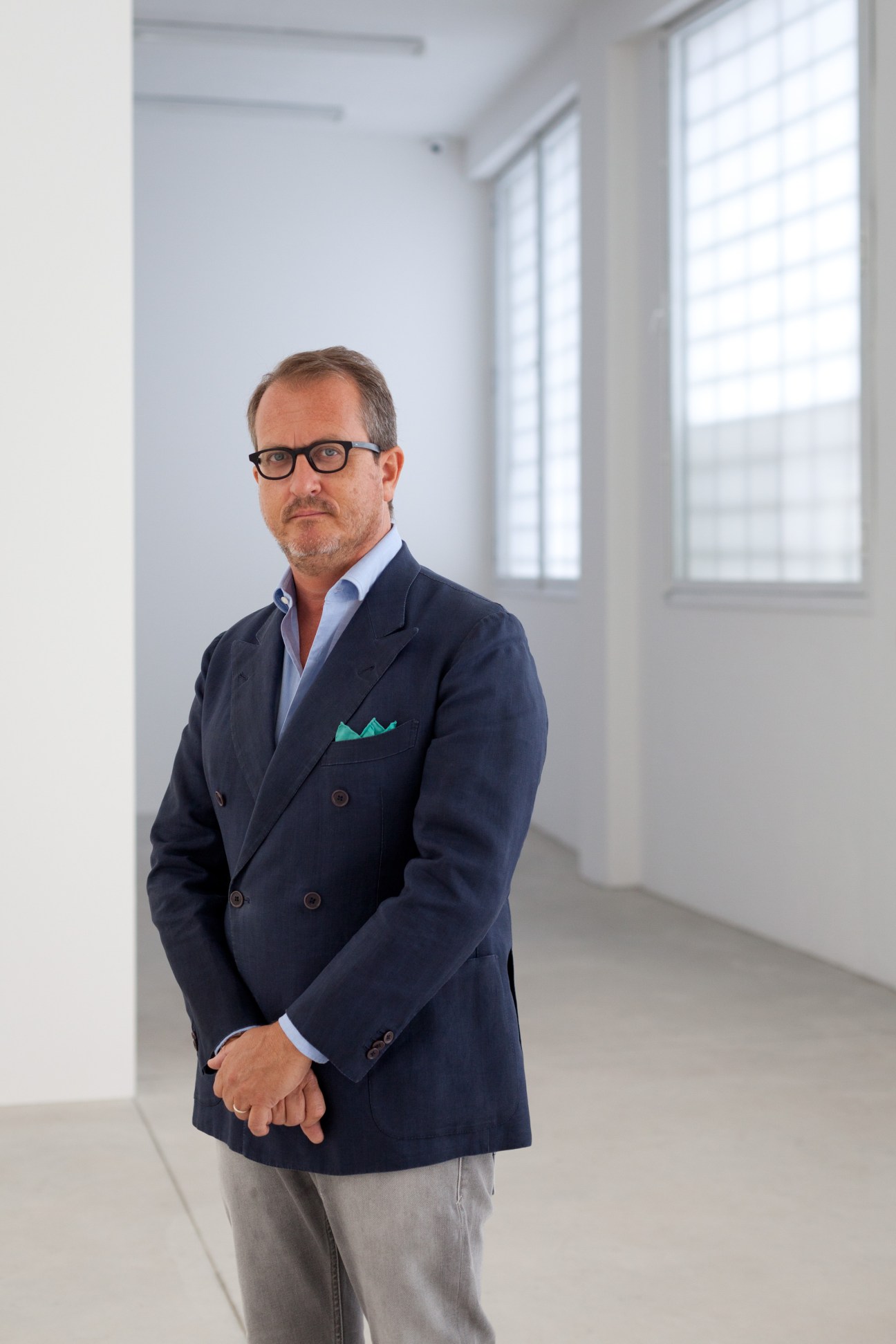 Art-gallery owner Franco Noero standing in a bright, minimalist white room with large windows.